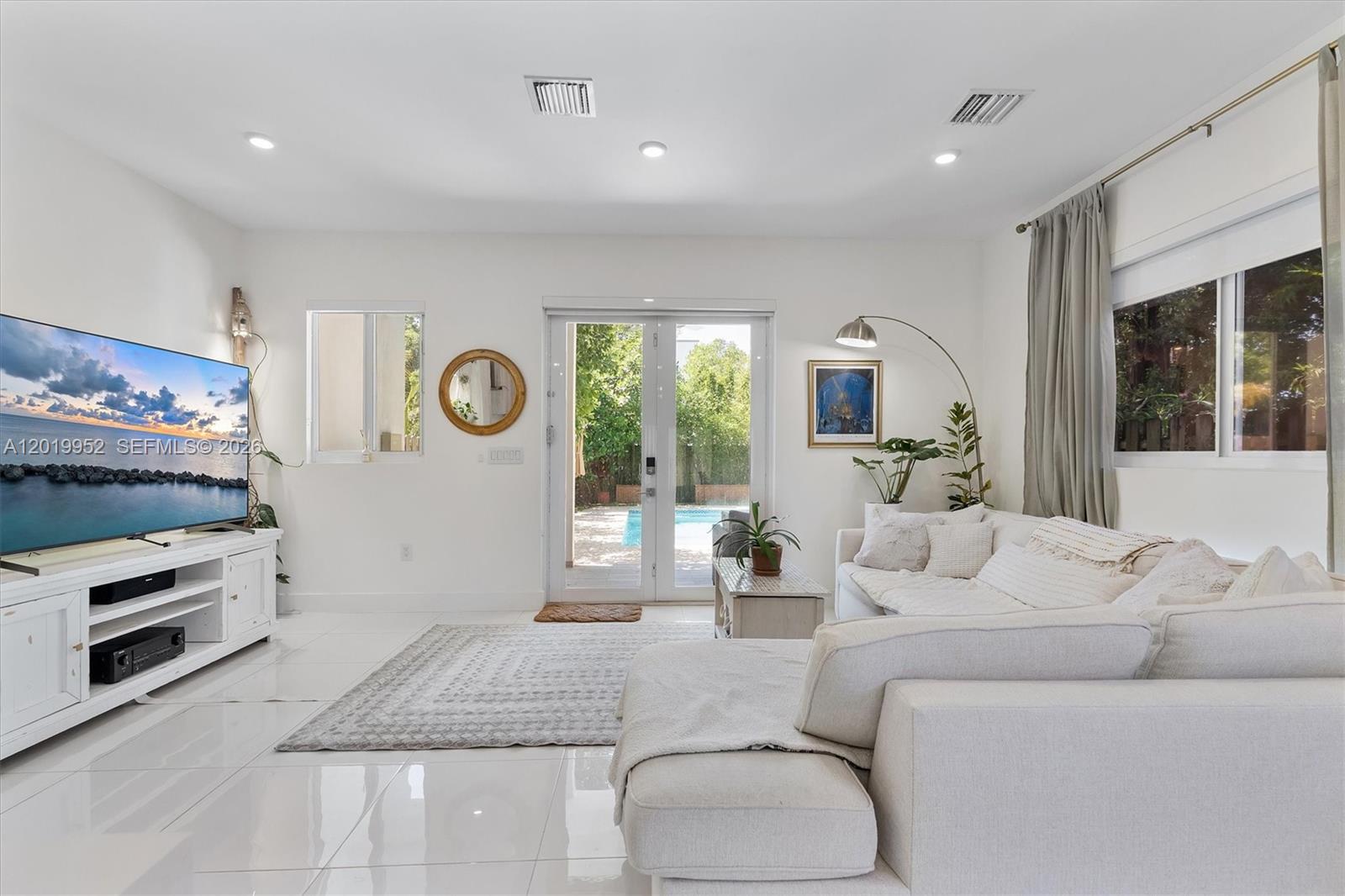 A bright living room features white tile floors, a large sectional sofa, and glass patio doors — 2920 SW 25th Ter # B, Miami FL 33133, MIAMI, FL