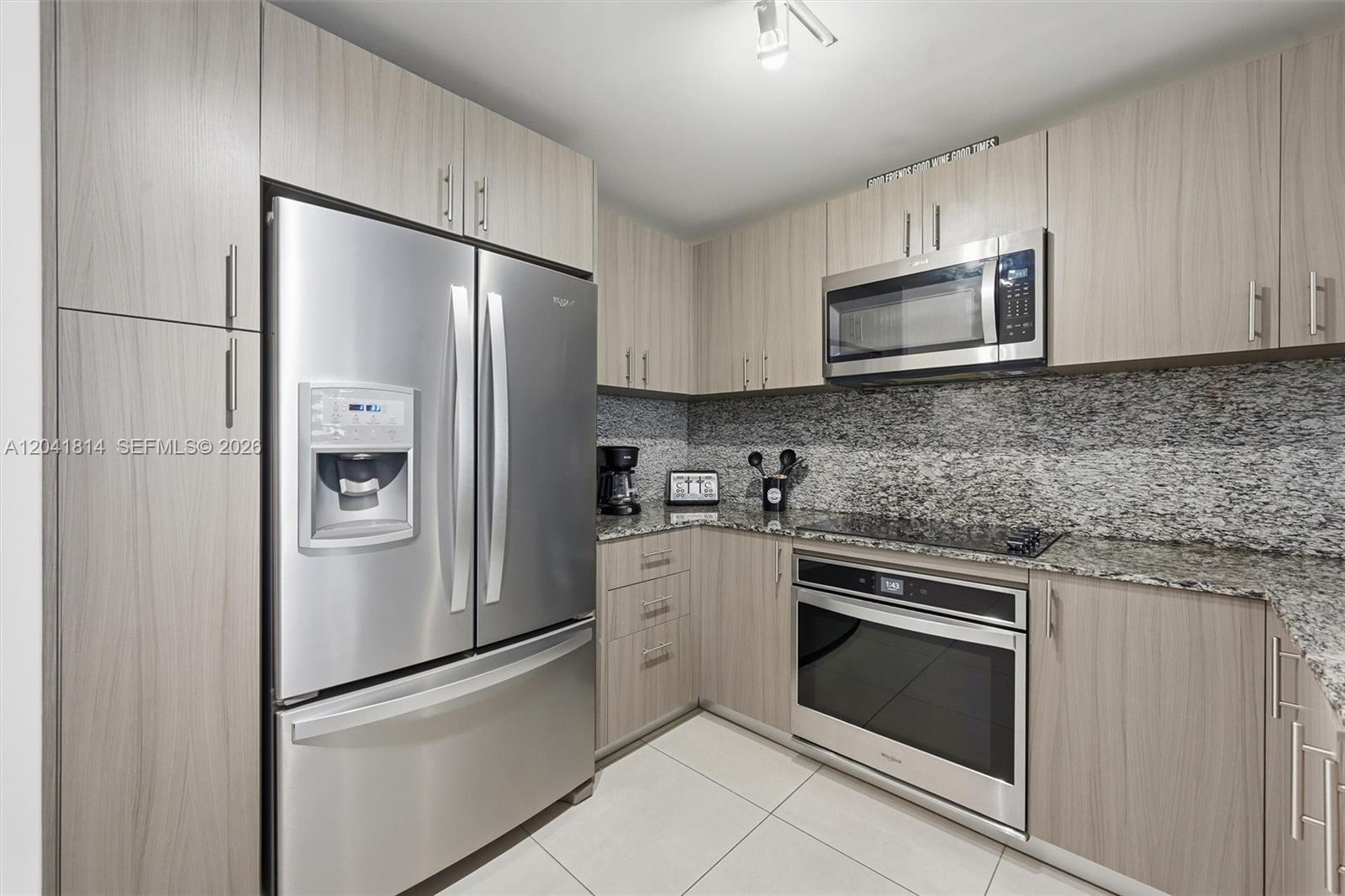 A modern kitchen features light wood cabinets, stainless steel appliances, and granite countertops — 5350 NW 84th Ave # 504, Doral FL 33166, DORAL, FL