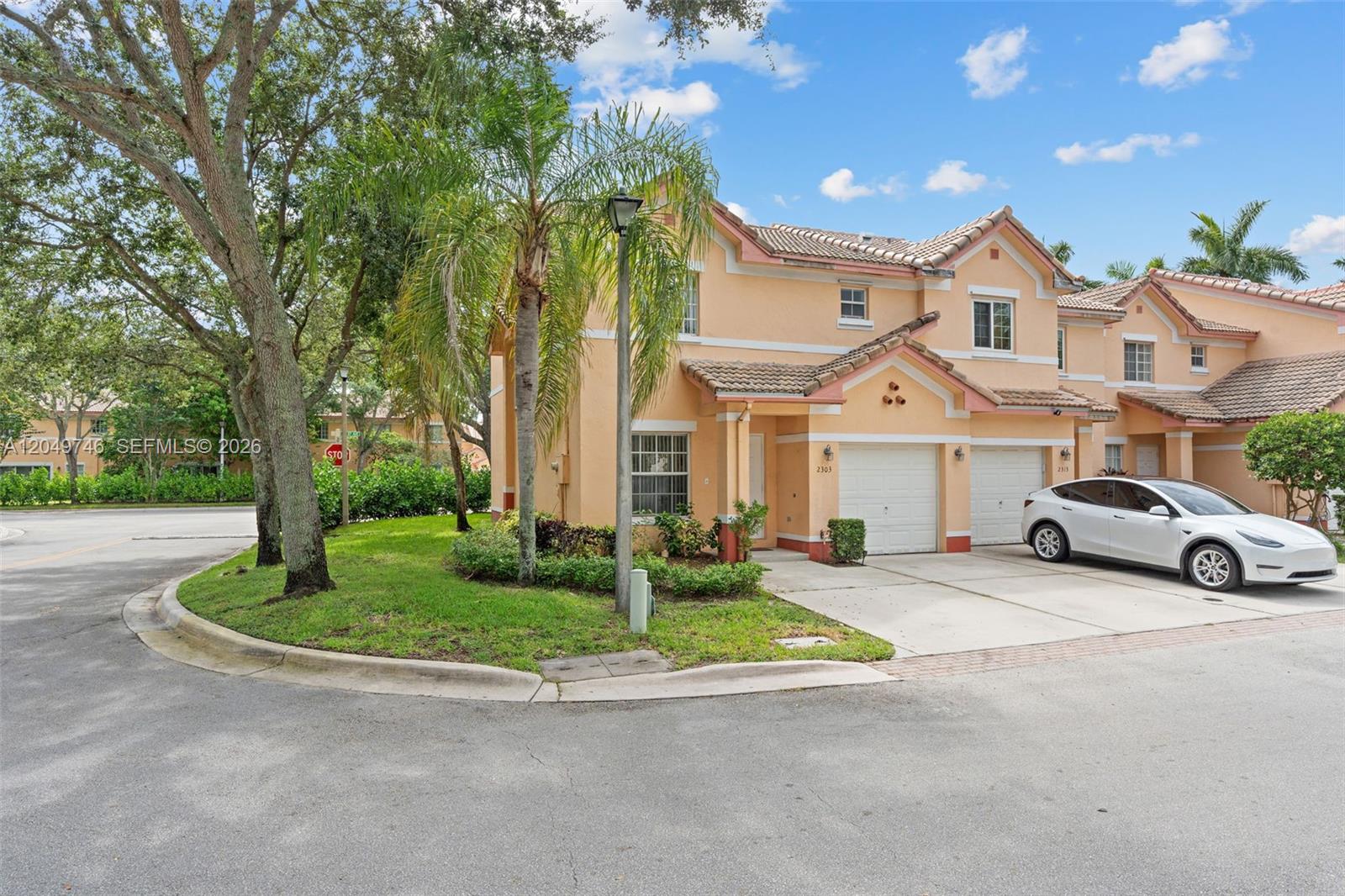A two-story peach-colored townhouse features a white garage and a white car parked outside — 2303 SW 87th Ter, Miramar FL 33025, MIRAMAR, FL