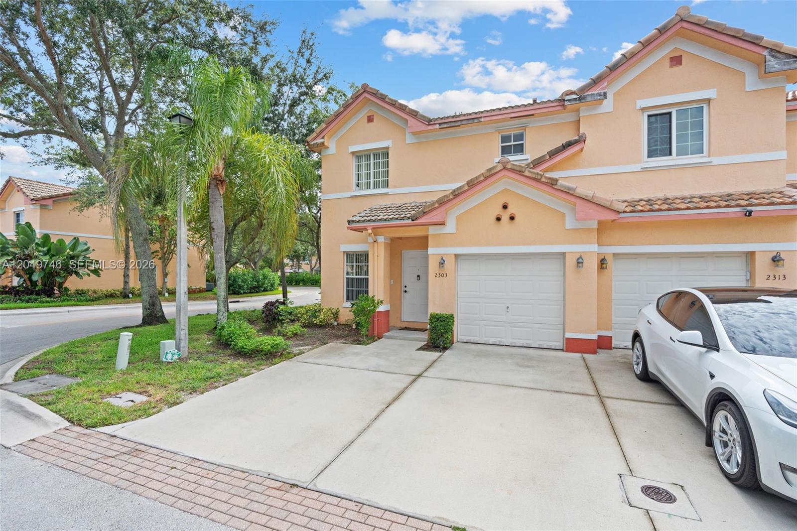 A two-story peach-colored townhouse with a white garage door and a driveway — 2303 SW 87th Ter, Miramar FL 33025, MIRAMAR, FL