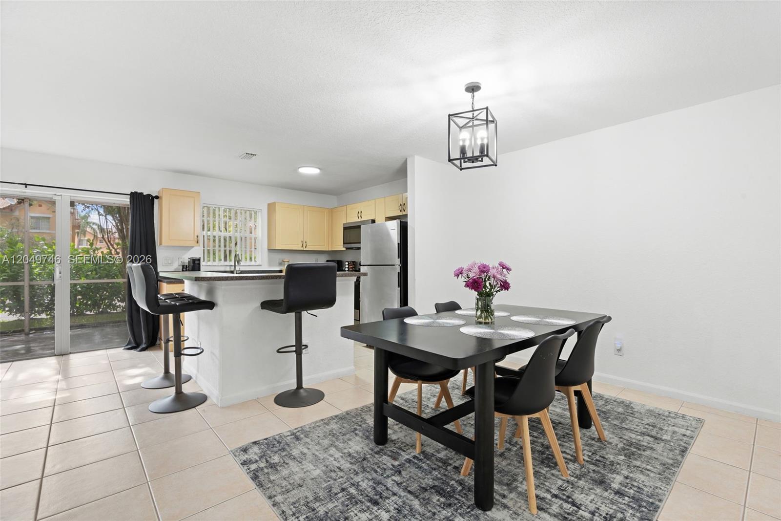 A dining area with a black table and chairs sits adjacent to a kitchen island — 2303 SW 87th Ter, Miramar FL 33025, MIRAMAR, FL