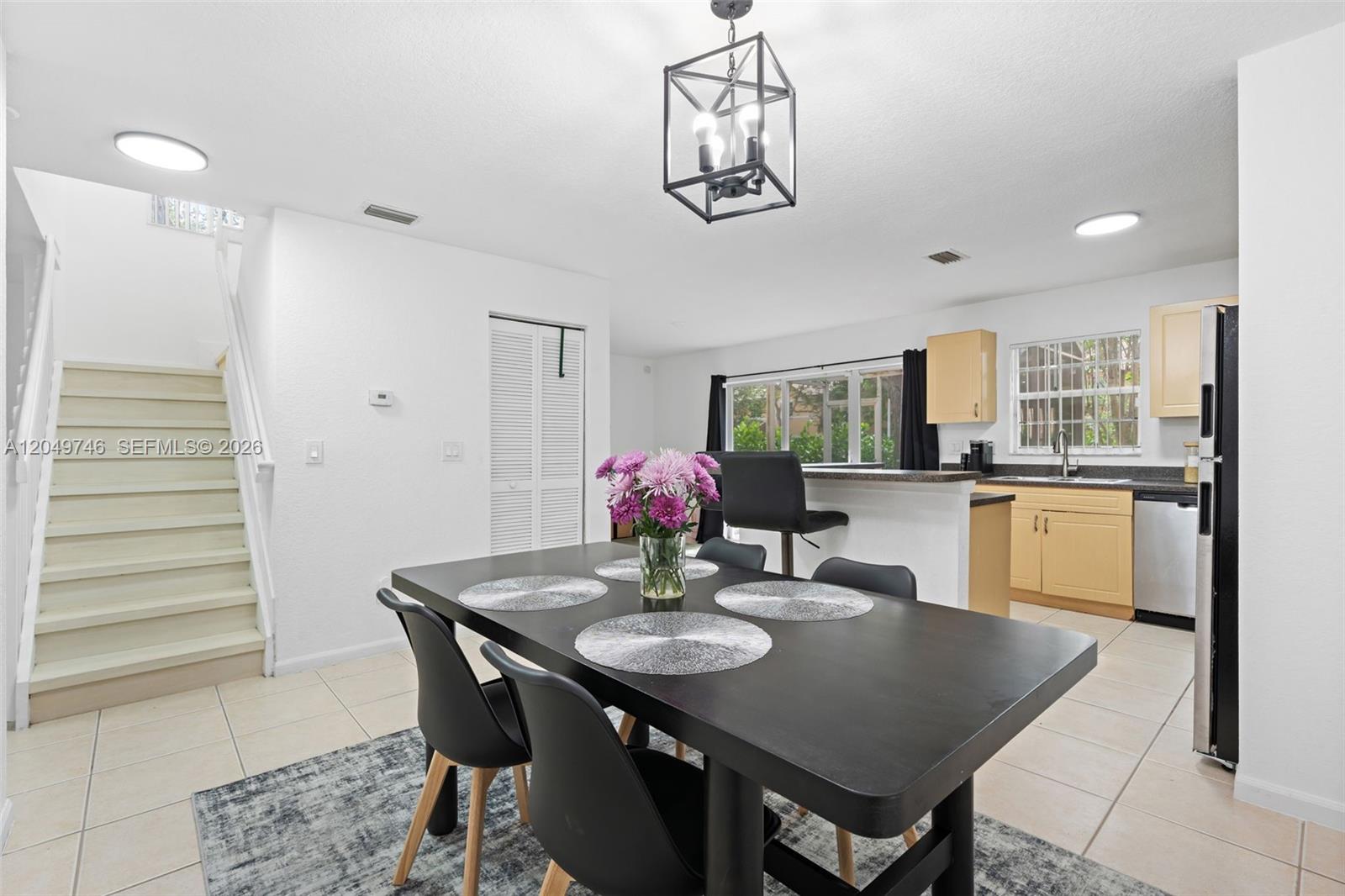 A dining area with a black table and chairs sits adjacent to a kitchen — 2303 SW 87th Ter, Miramar FL 33025, MIRAMAR, FL