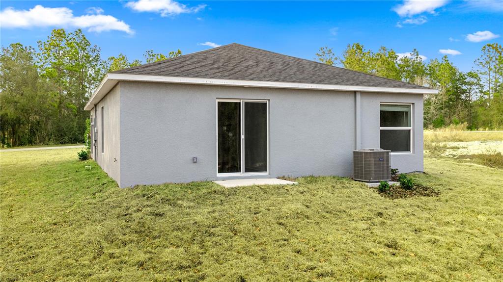 The exterior of a gray stucco house features a sliding glass door and an AC unit — 8140 SW 44TH TERRACE, OCALA, FL