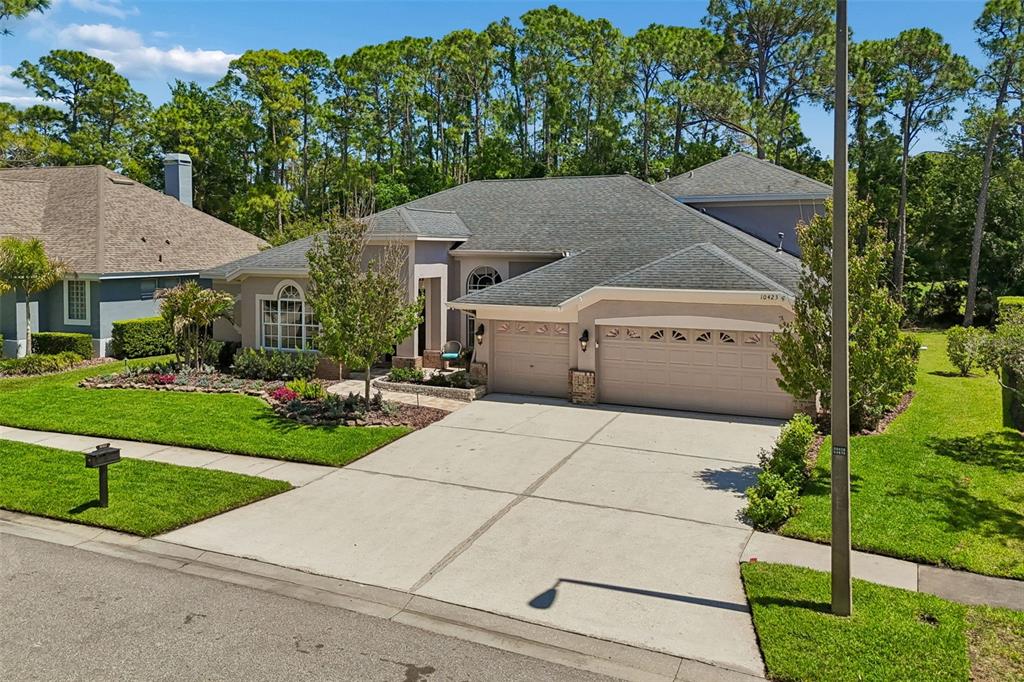 An exterior view of a single-story suburban house with a three-car garage and lawn — 10423 GREENHEDGES DRIVE, TAMPA, FL