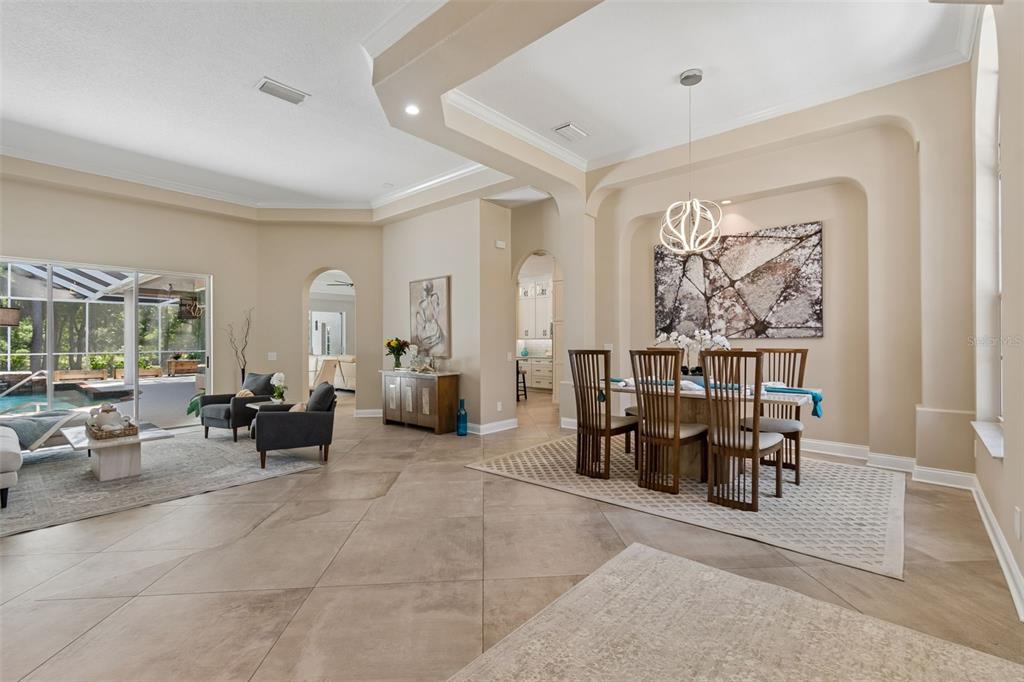 An open-concept dining and living area features tile floors, neutral walls, and a pool view — 10423 GREENHEDGES DRIVE, TAMPA, FL