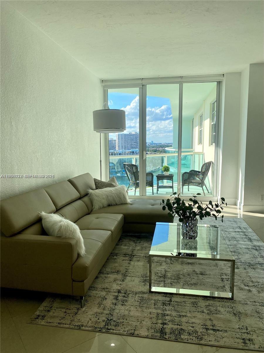 A living room features a beige sectional sofa, glass coffee table, and a balcony view — 3801 S Ocean Dr, Hollywood FL 33019, HOLLYWOOD, FL