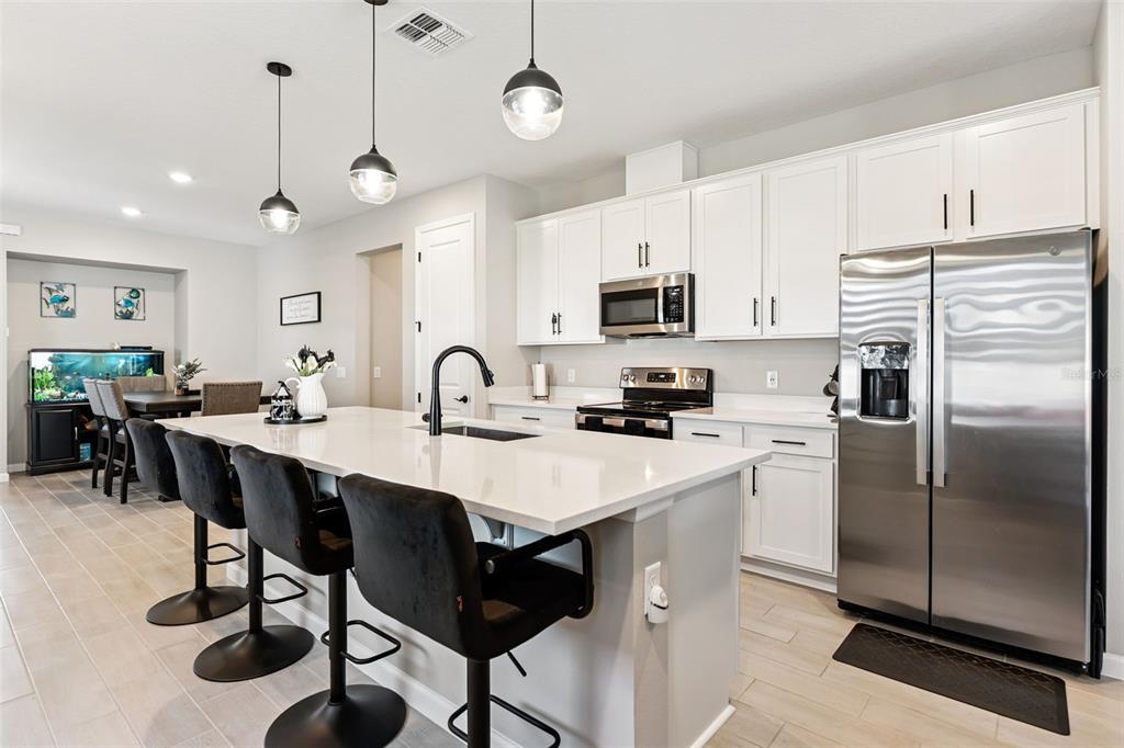 A modern kitchen features a white island, stainless steel appliances, and white cabinetry — 891 BLUE CREEK DRIVE, HAINES CITY, FL