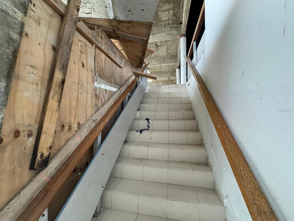An indoor staircase with white tiled steps, wooden handrails, and plywood construction barriers — 1064 AV. ISLA VERDE, CAROLINA, PR