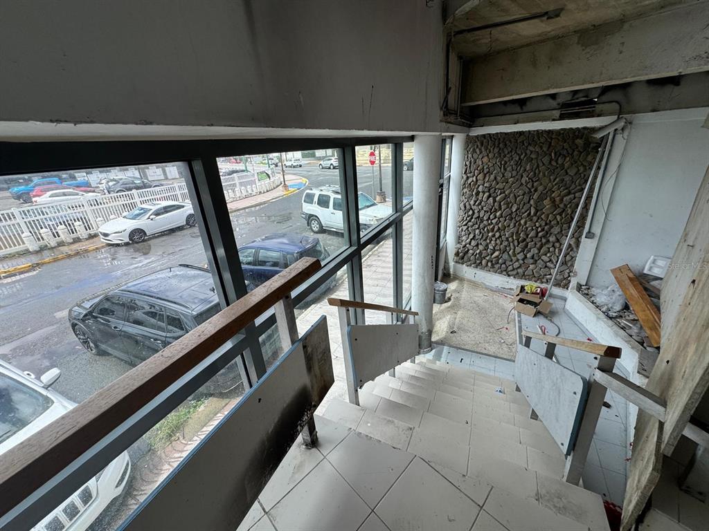 An interior staircase with a stone feature wall overlooks a street with parked cars — 1064 AV. ISLA VERDE, CAROLINA, PR