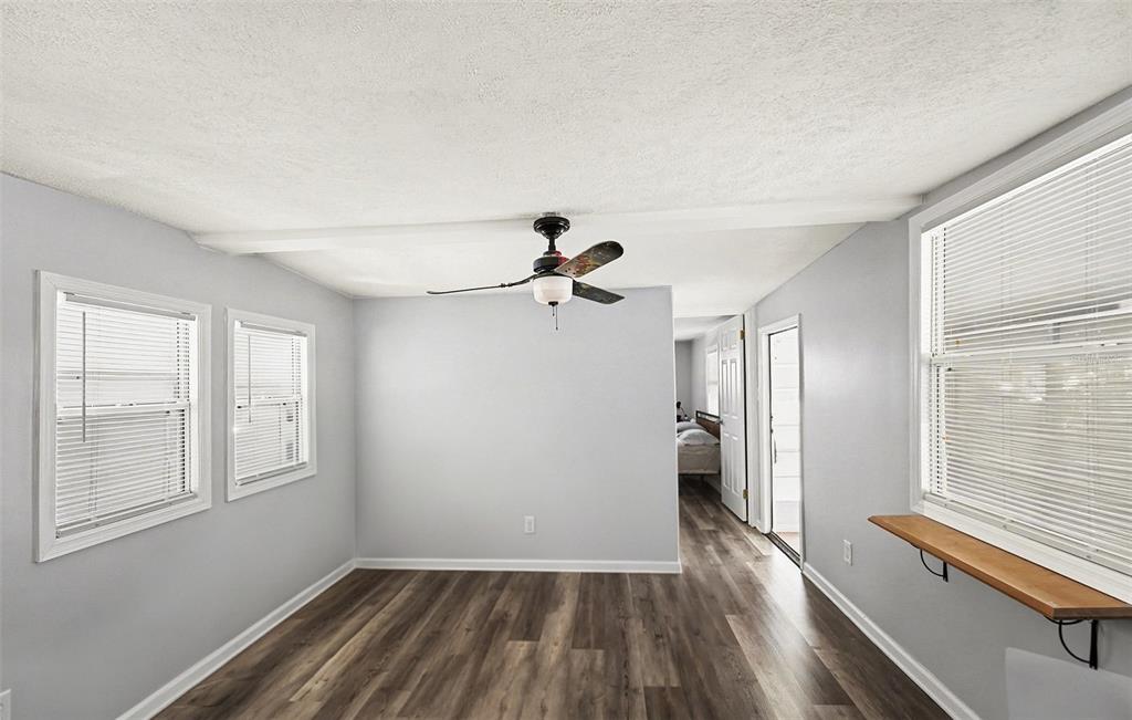A room with light gray walls, wood-look flooring, a ceiling fan, and multiple windows — 9790 66TH STREET N UNIT 74, PINELLAS PARK, FL