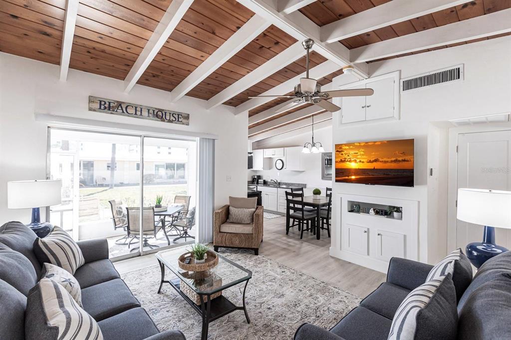 A living room with a wood-plank ceiling, ceiling fan, and sliding glass doors to a patio — 6006 MIDNIGHT PASS ROAD UNIT 14, SARASOTA, FL