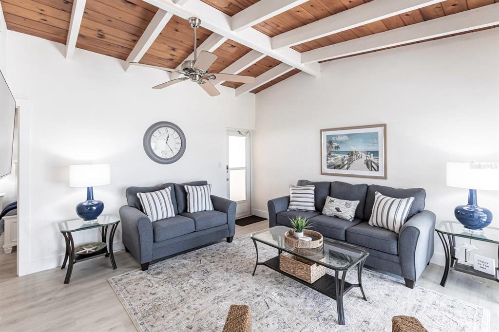 A living room features dark gray sofas, a glass coffee table, and a wood-paneled ceiling — 6006 MIDNIGHT PASS ROAD UNIT 14, SARASOTA, FL