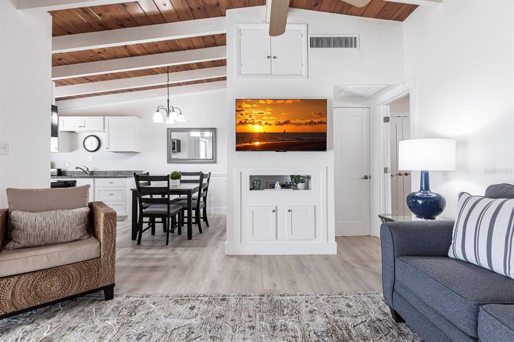 A living room with a vaulted wood-beam ceiling, white walls, and a wall-mounted television — 6006 MIDNIGHT PASS ROAD UNIT 14, SARASOTA, FL