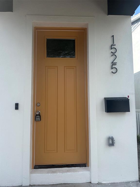 A mustard-colored front door with a small window sits next to a black mailbox — 1525 29TH AVENUE N, ST PETERSBURG, FL