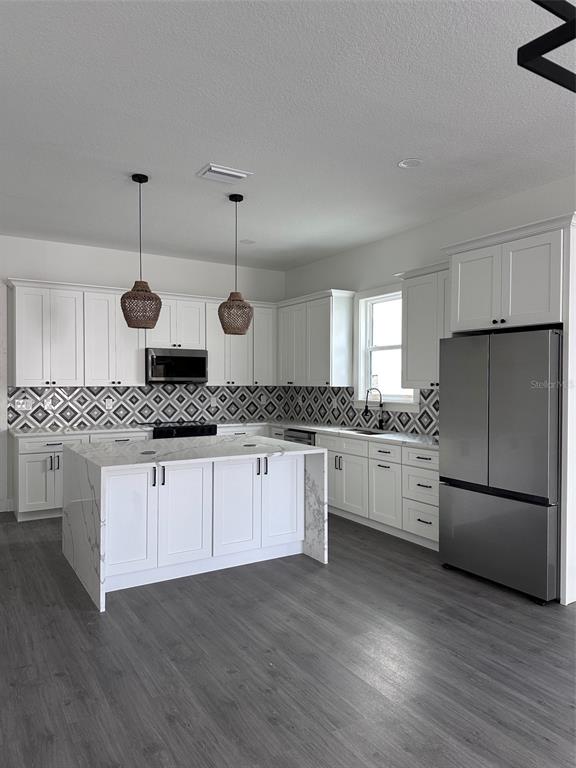 A modern kitchen features white cabinetry, a marble-topped island, and a geometric patterned tile backsplash — 1525 29TH AVENUE N, ST PETERSBURG, FL