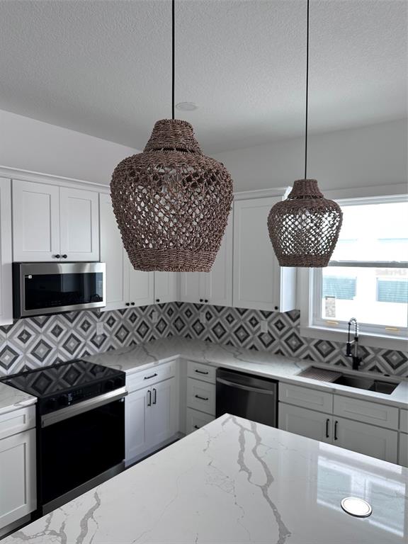 A modern kitchen features white cabinets, marble-look countertops, a geometric backsplash, and two woven pendant lights — 1525 29TH AVENUE N, ST PETERSBURG, FL