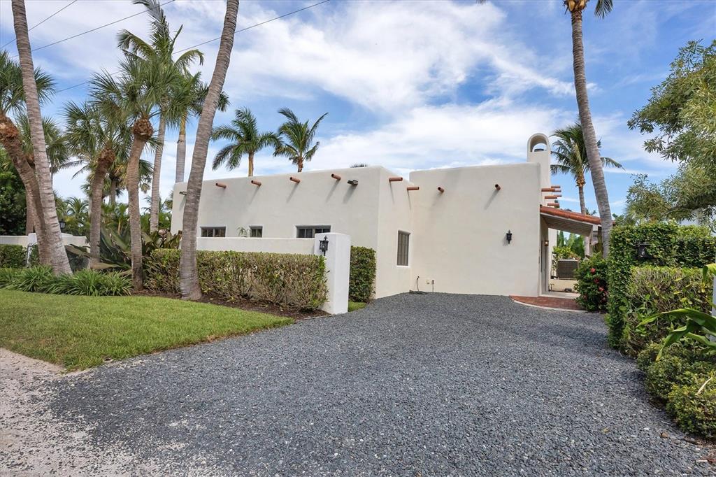 A white stucco house with viga beams and a gravel driveway sits among palm trees — 1021 10TH STREET W, BOCA GRANDE, FL