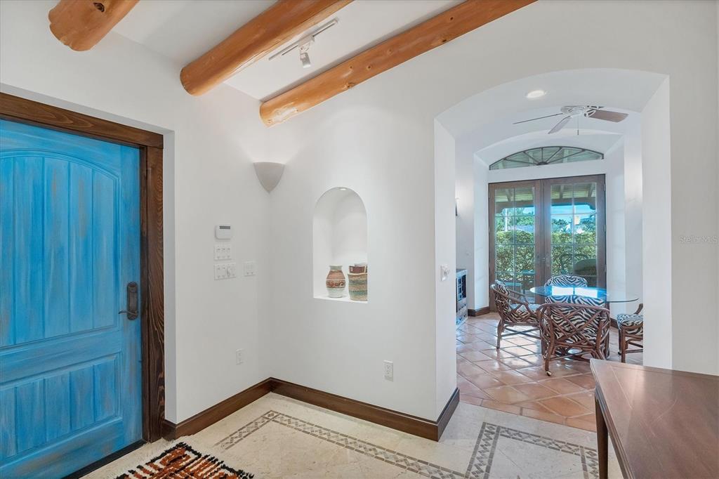 An entryway with a blue door, wood ceiling beams, a wall niche, and tiled floors — 1021 10TH STREET W, BOCA GRANDE, FL