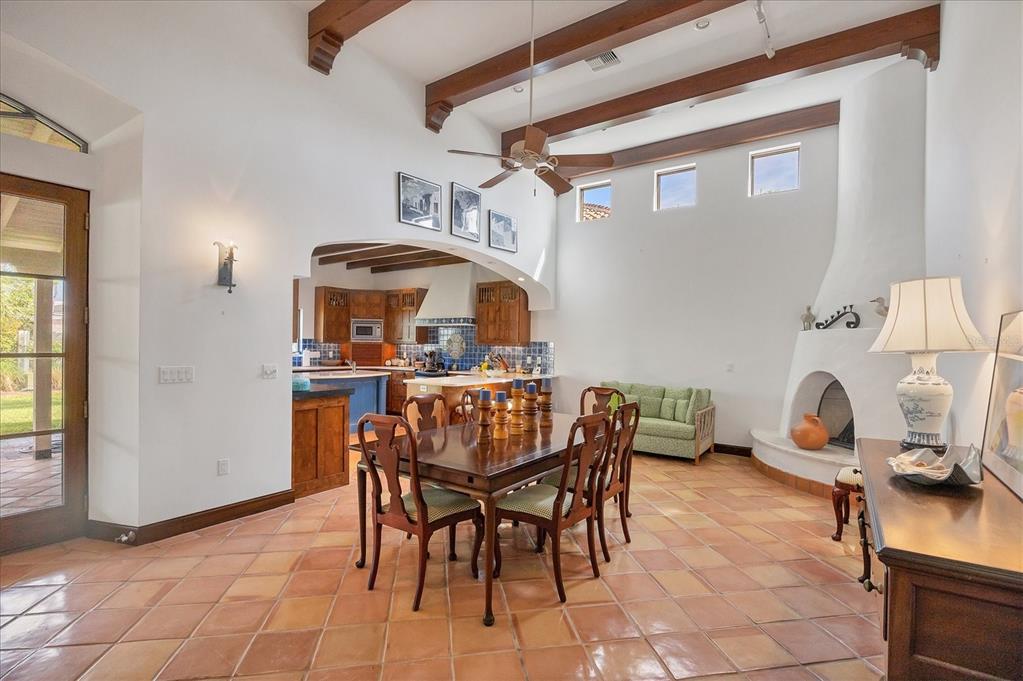A dining room with tile floors, wooden beams, and a kiva-style fireplace near the kitchen — 1021 10TH STREET W, BOCA GRANDE, FL