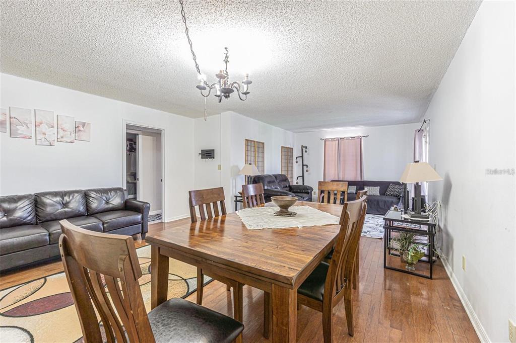 A dining area with a wooden table and chairs opens into a living room space — 14820 RUE DE BAYONNE UNIT 301, CLEARWATER, FL