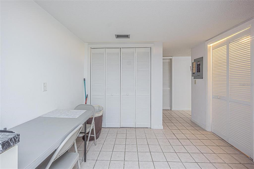 A room with white walls, tiled flooring, and multiple sets of white louvered closet doors — 14820 RUE DE BAYONNE UNIT 301, CLEARWATER, FL