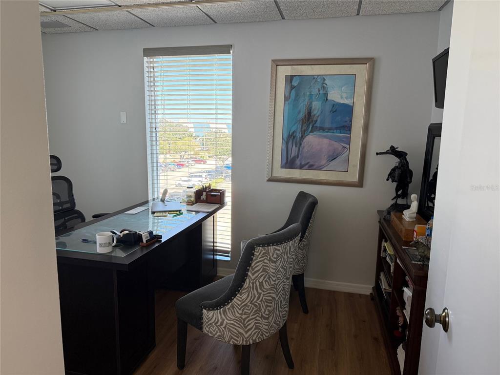 An office features a dark desk, two patterned chairs, a window, and a framed painting — 1219 S EAST AVENUE UNIT 3-304, SARASOTA, FL
