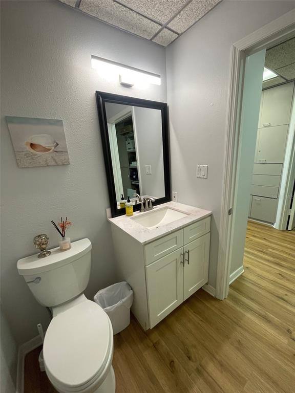 A bathroom features a white vanity, a black-framed mirror, a toilet, and light wood flooring — 1219 S EAST AVENUE UNIT 3-304, SARASOTA, FL