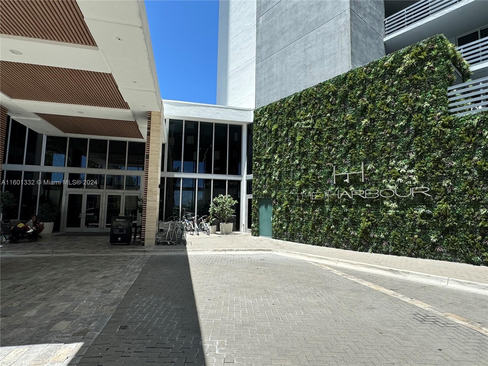 The exterior entrance of a building features a living green wall and a paved driveway — 16385 Biscayne Blvd # 2421, North Miami Beach FL 33160, NORTH MIAMI BEACH, FL