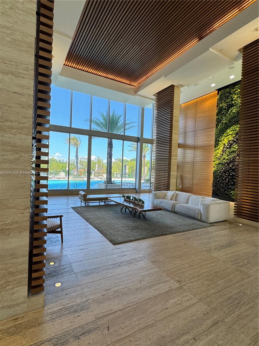 A modern lobby features a living wall, floor-to-ceiling windows, and views of an outdoor pool — 16385 Biscayne Blvd # 2421, North Miami Beach FL 33160, NORTH MIAMI BEACH, FL