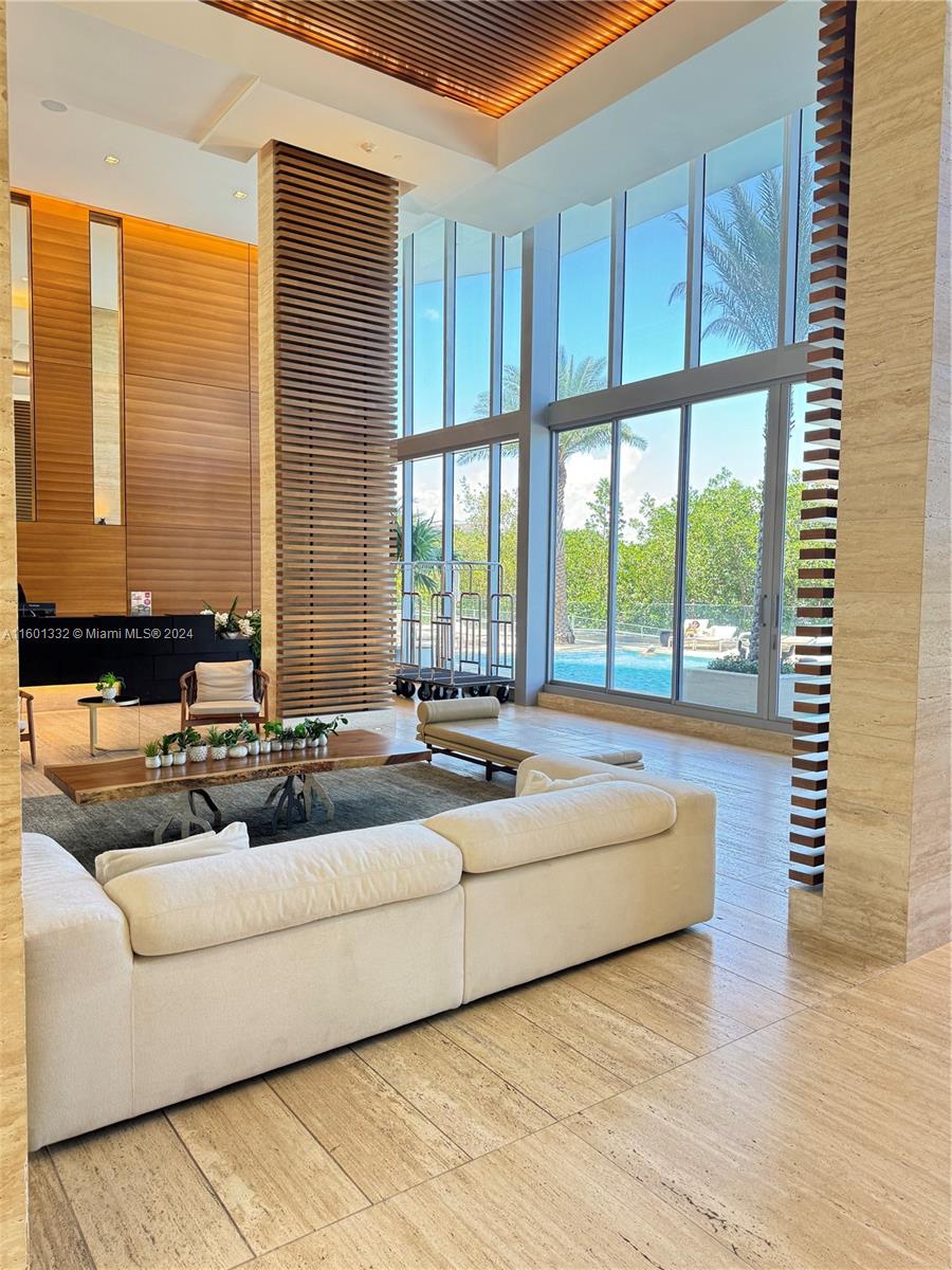 A modern lobby features wood-slat columns, floor-to-ceiling windows, and a view of an outdoor pool — 16385 Biscayne Blvd # 2421, North Miami Beach FL 33160, NORTH MIAMI BEACH, FL