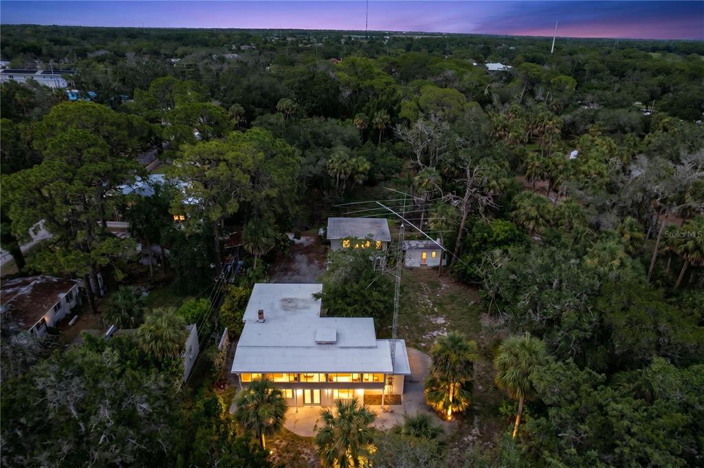 An aerial view shows a modern house with a large antenna tower in a wooded area — 1275 MICKLER LANE, TARPON SPRINGS, FL