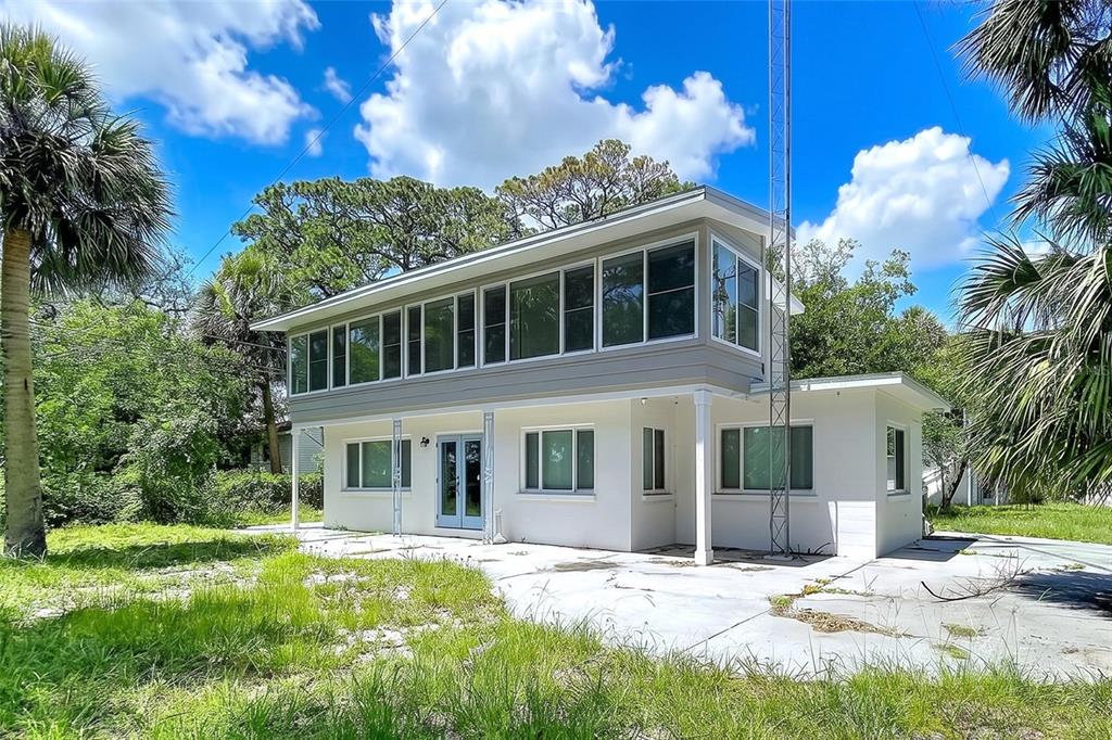 A two-story house with a white exterior, large windows, and a metal antenna tower — 1275 MICKLER LANE, TARPON SPRINGS, FL