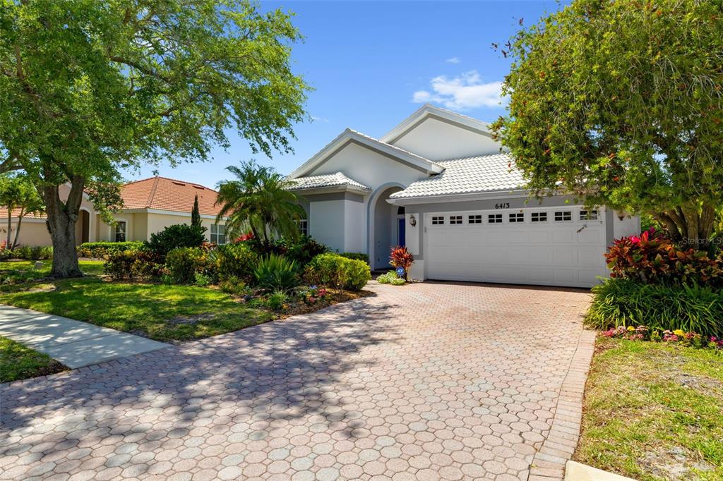 A single-story house with a white garage, tiled roof, and a paved driveway — 6413 GRAND POINT AVENUE, BRADENTON, FL