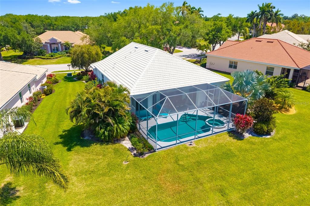 An aerial view of a house with a white roof, screened pool, and large lawn — 6413 GRAND POINT AVENUE, BRADENTON, FL