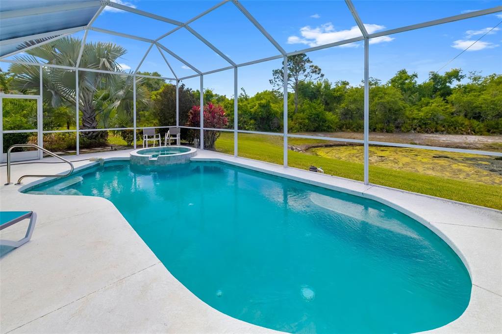 A swimming pool and hot tub are enclosed by a screened lanai overlooking a pond — 6413 GRAND POINT AVENUE, BRADENTON, FL