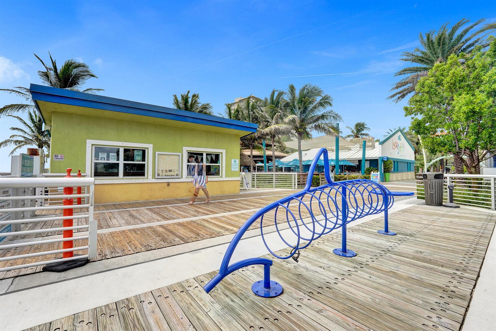 A blue metal bike rack sits on a wooden boardwalk near a green building — 0 NW 15th Avenue, Pompano Beach FL 33069, POMPANO BEACH, FL