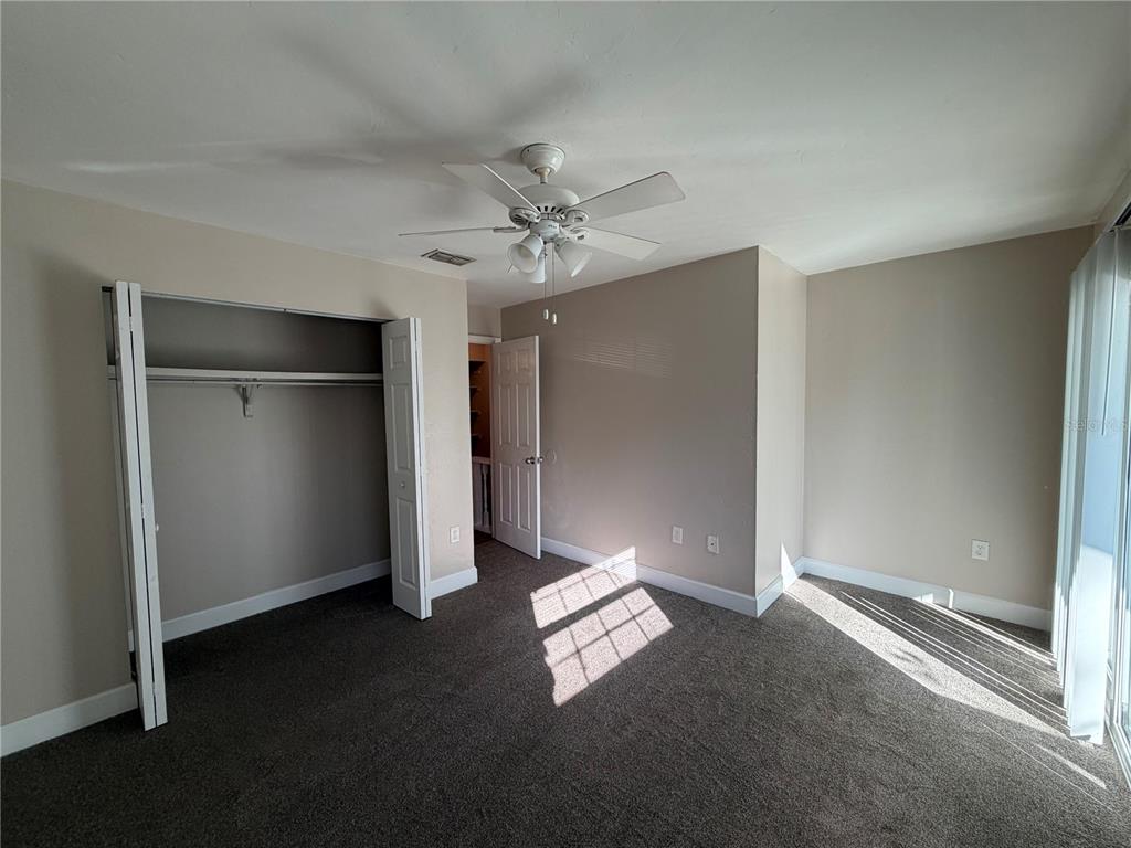 A bedroom with dark carpet, a ceiling fan, a closet, and a white door — 1718 SW 69TH TERRACE UNIT A, GAINESVILLE, FL