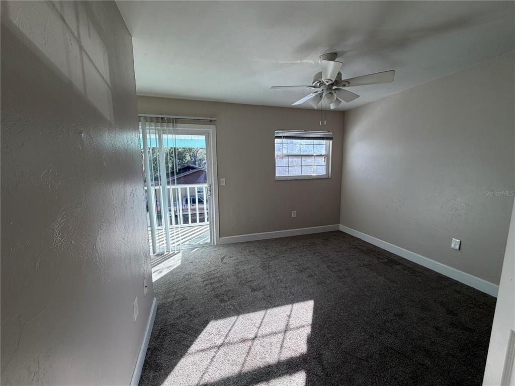 A bedroom with gray carpet, a ceiling fan, a window, and a sliding glass door — 1718 SW 69TH TERRACE UNIT A, GAINESVILLE, FL