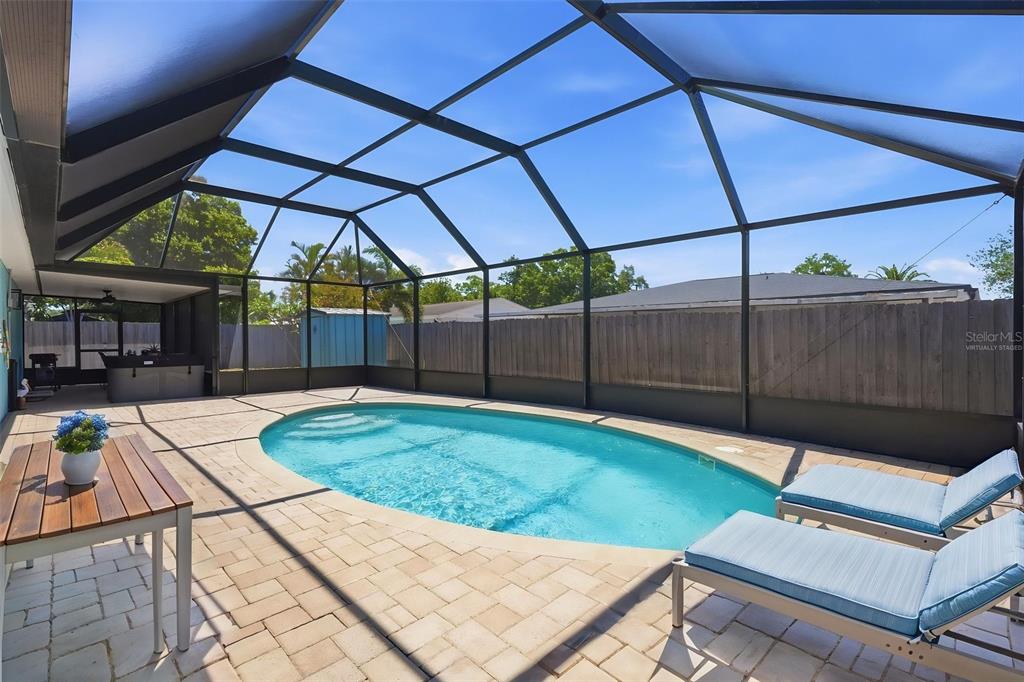 A screened-in patio features a swimming pool, brick pavers, and two lounge chairs — 9276 N 79TH AVENUE, SEMINOLE, FL