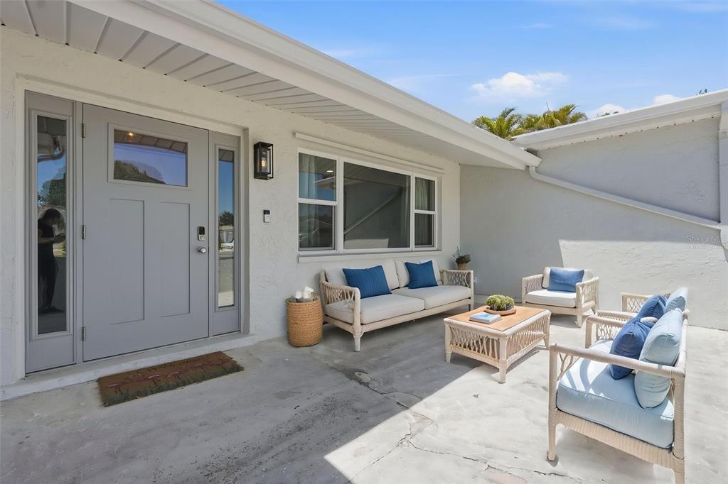 A patio with outdoor furniture sits in front of a house with a gray door — 9276 N 79TH AVENUE, SEMINOLE, FL