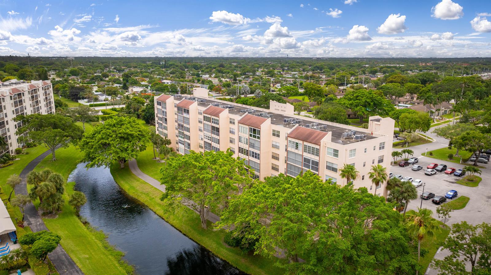 An aerial view shows a multi-story apartment building next to a canal and parking lot — 14527 Bonaire Boulevard # 203, Delray Beach FL 33446, DELRAY BEACH, FL