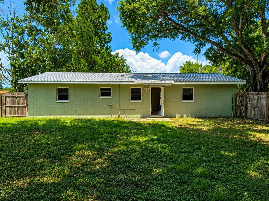 The exterior of a single-story concrete block house with a metal roof and green paint — 516 TANGLEWOOD DRIVE, AUBURNDALE, FL