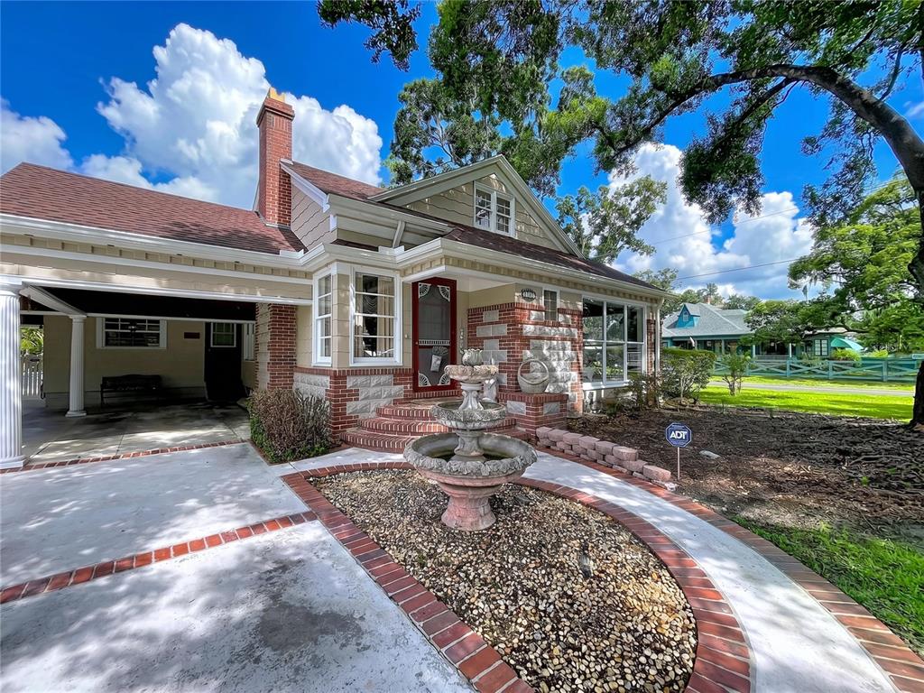 A single-story house with a brick chimney, stone accents, and a stone fountain in front — 607 N MERRIN STREET, PLANT CITY, FL