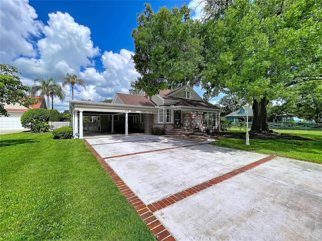 A single-story house with a brick-accented driveway, carport, and large trees in the front yard — 607 N MERRIN STREET, PLANT CITY, FL