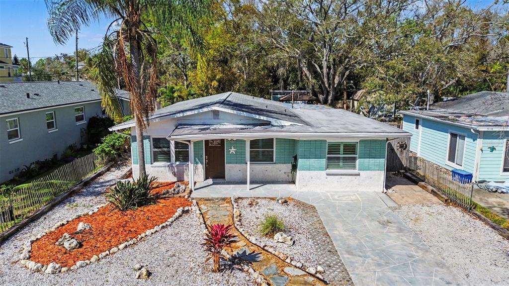 A single-story house with teal siding, a flat roof, and a stone-paved front yard — 318 BATH STREET, TARPON SPRINGS, FL