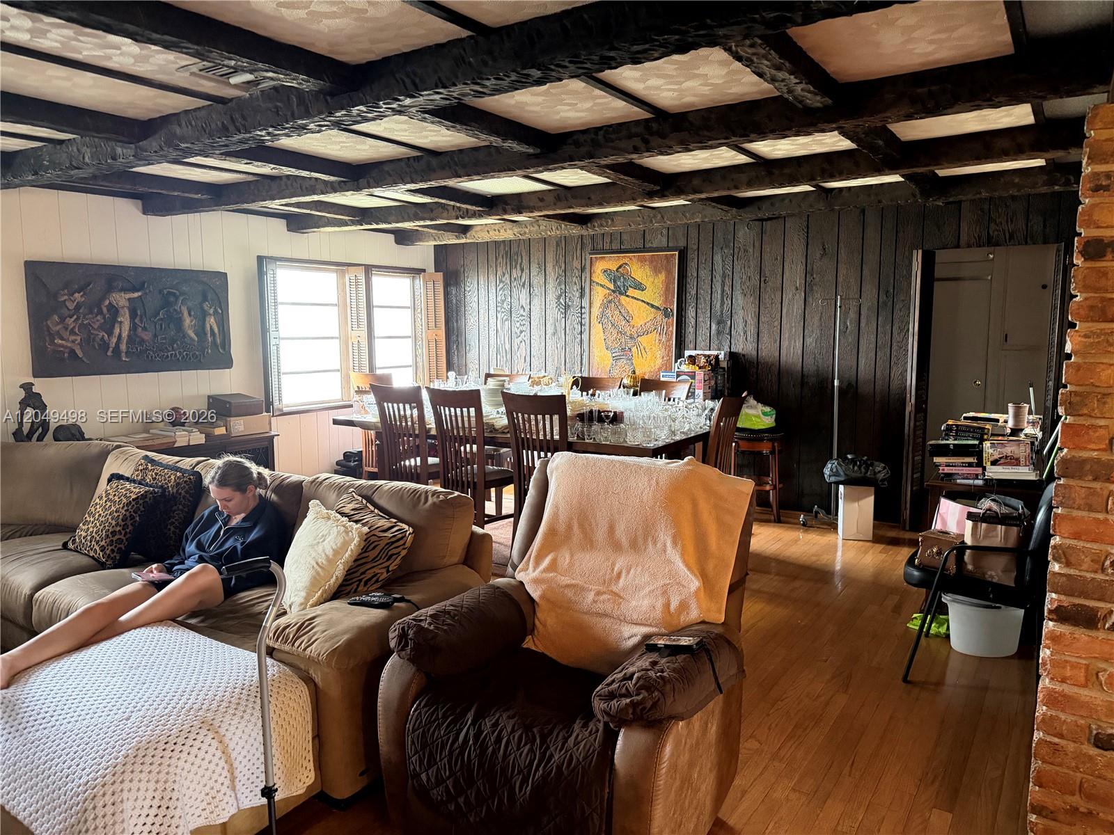 A living and dining area features dark wood-paneled walls and a coffered ceiling with beams — 291 W 59th St, Hialeah FL 33012, HIALEAH, FL