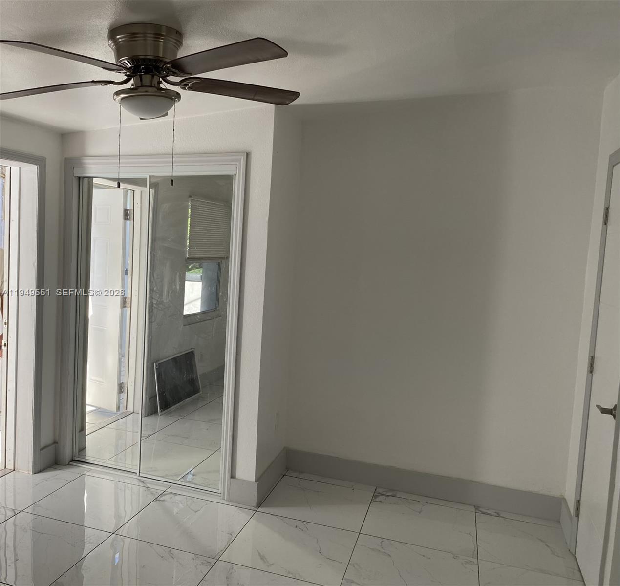 A room with white tile floors, a ceiling fan, and mirrored sliding closet doors — 6045 Buchanan St # 1, Hollywood FL 33024, HOLLYWOOD, FL