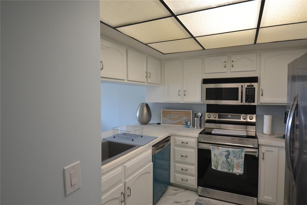 A kitchen features white cabinets, stainless steel appliances, and a drop ceiling with recessed lighting — 238 MARINER DRIVE, TARPON SPRINGS, FL
