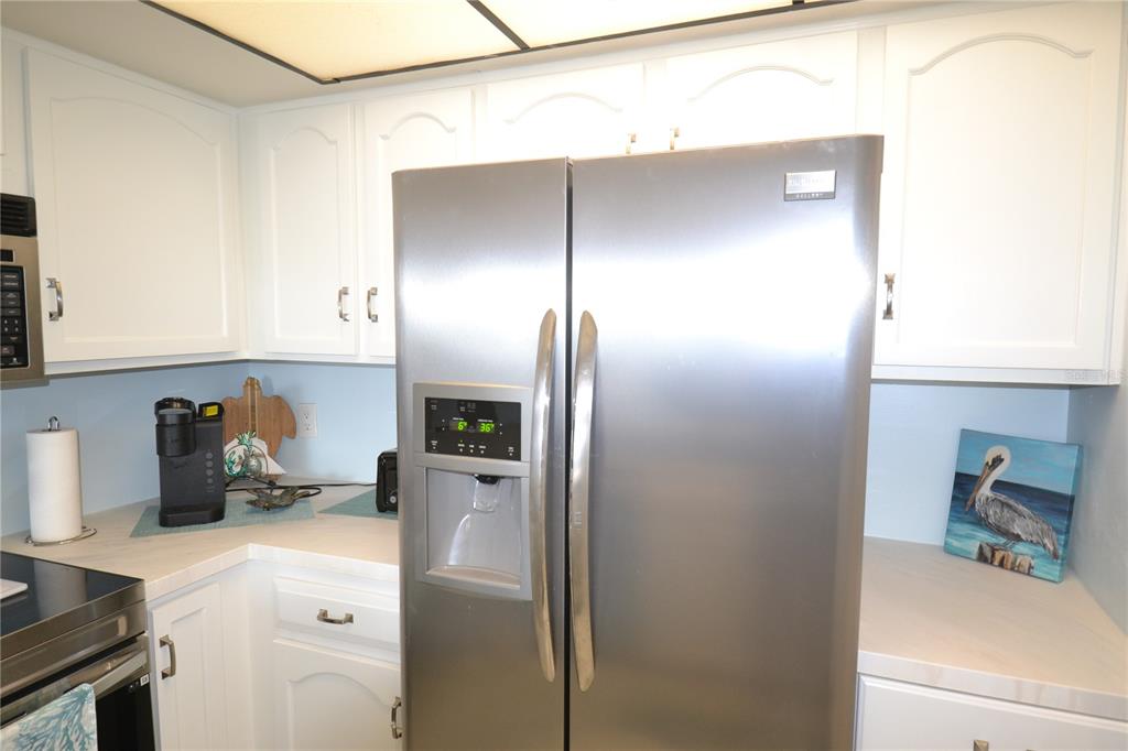 A stainless steel refrigerator stands in a kitchen with white cabinets and light countertops — 238 MARINER DRIVE, TARPON SPRINGS, FL