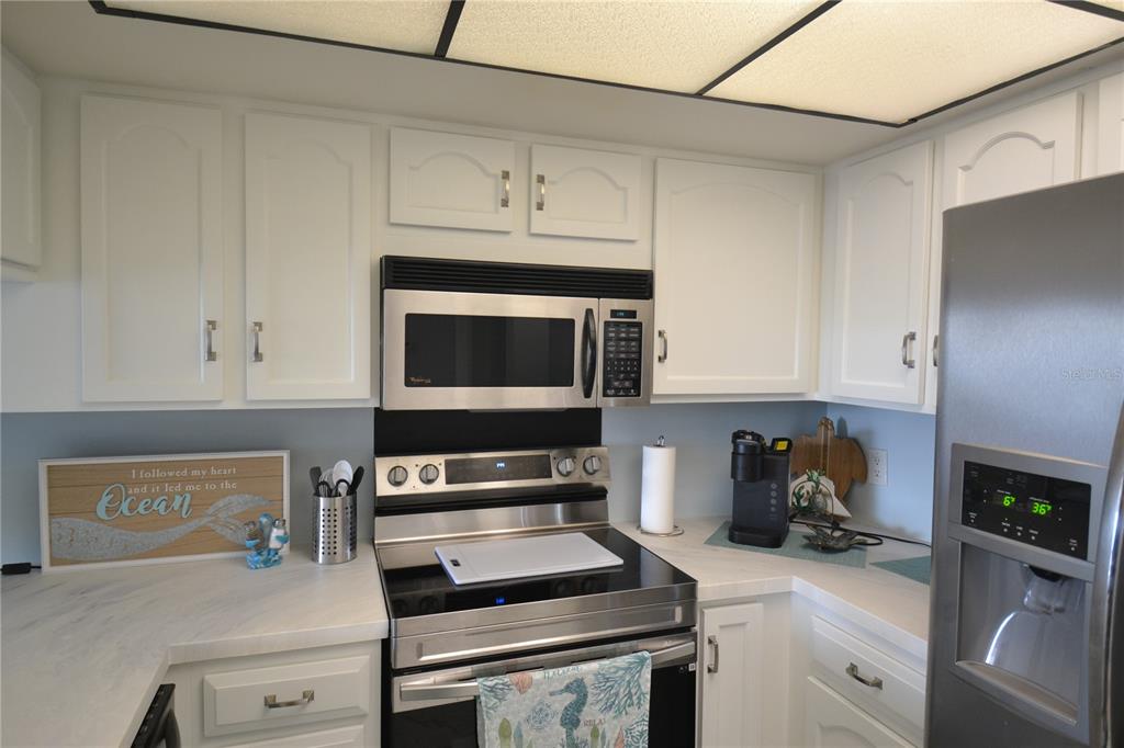 A kitchen features white cabinets, stainless steel appliances, and light-colored countertops — 238 MARINER DRIVE, TARPON SPRINGS, FL